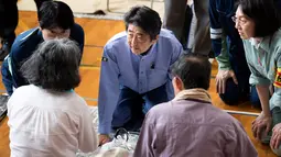 Perdana Menteri Jepang Shinzo Abe mengunjungi lokasi penampungan korban banjir di Mabi, Prefektur Okayama, Rabu (11/7). Sebelumnya, Abe sudah membatalkan rencana perjalanan luar negeri karena bencana yang kian memburuk. (AFP/Martin BUREAU)