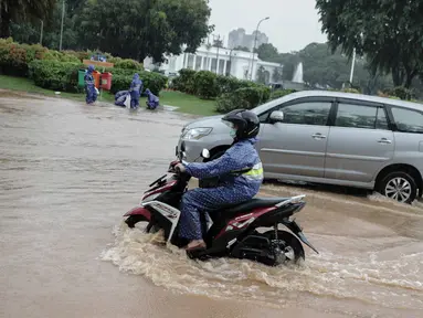 Kendaraan bermotor melintasi genangan air di Jalan Medan Merdeka Barat, Jakarta, Kamis (24/1/2020). Hujan deras yang mengguyur Jakarta sejak pagi tadi mengakibatkan genangan air di Jalan Medan Merdeka Barat. (Liputan6.com/Faizal Fanani)
