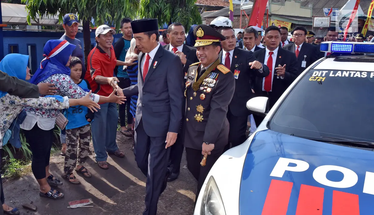 Presiden Joko Widodo menyalami warga saat berjalan menuju lokasi upacara HUT ke-72 TNI di Pelabuhan Indah Kiat, Banten (5/10). Karena kendaraan terjebak macet, Presiden Jokowi memilih berjalan kaki menuju lokasi upacara. (Liputan6.com/Pool/Agus Suparto)