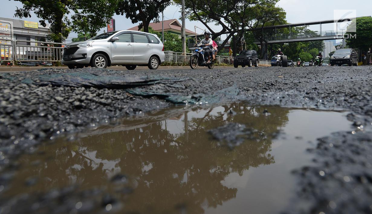 Sejumlah kendaraan melewati jalan berlubang yang masih tergenang air di ruas Jalan Lapangan Ros, Tebet, Jakarta, Sabtu (11/5/2019). Jalan-jalan berlubang yang terisi air tersebut dapat mengakibatkan kecelakaan bagi pengendara kendaraan bermotor. (merdeka.com/Imam Buhori)