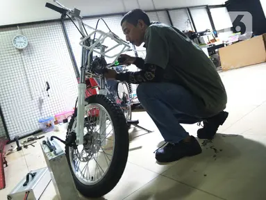 Seorang mekanik memodifikasi motor di Jakarta, Selasa (29/3/2022). Modifikasi motor tersebut merupakan konversi  bahan bakar minyak ke motor listrik. (merdeka.com/Imam Buhori)