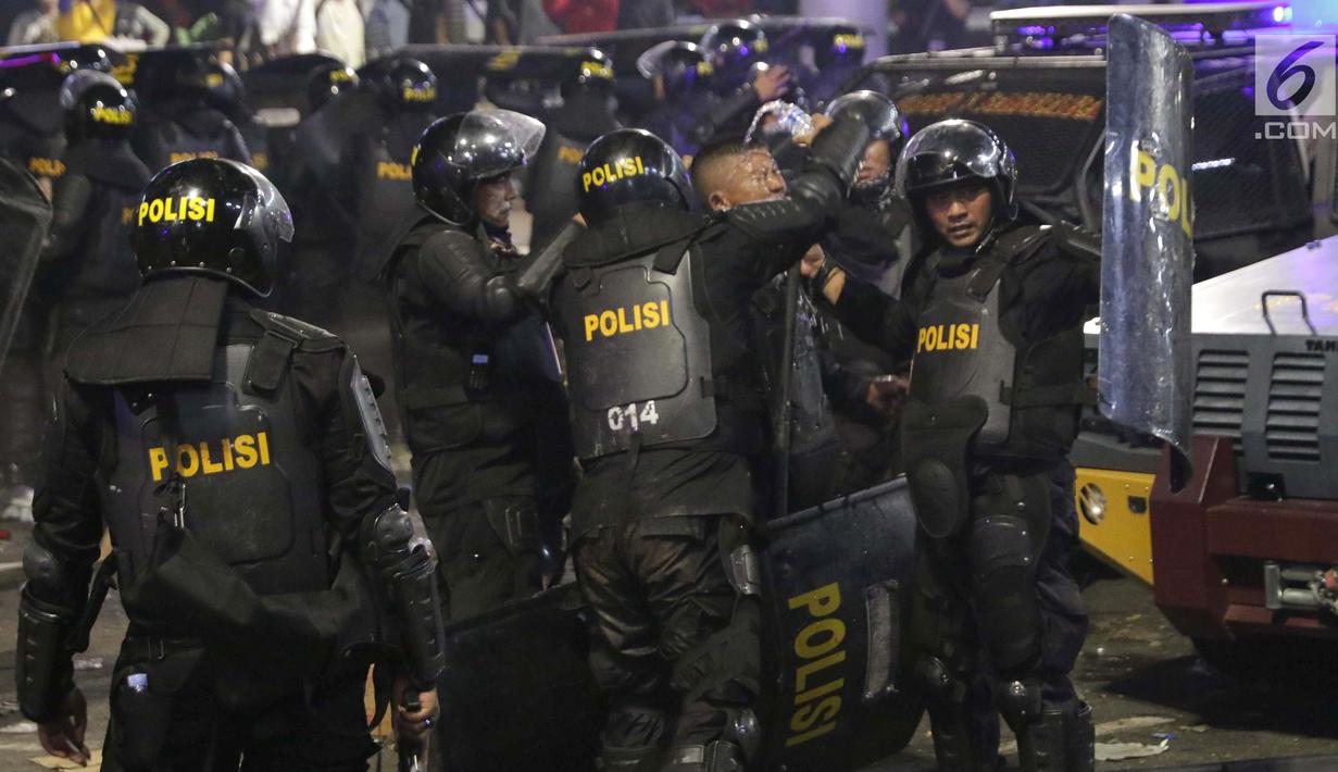 Personil Kepolisian dari satuan Brimob beristirahat sambil minum di sela-sela menghalau massa yang berlaku anarkis di sekitar depan Gedung Bawaslu, Jalan MH Thamrin, Jakarta, Rabu (22/5/2019). Aksi unjuk rasa yang dimotori GNKR berakhir ricuh. (Liputan6.com/HelmiFithriansyah)