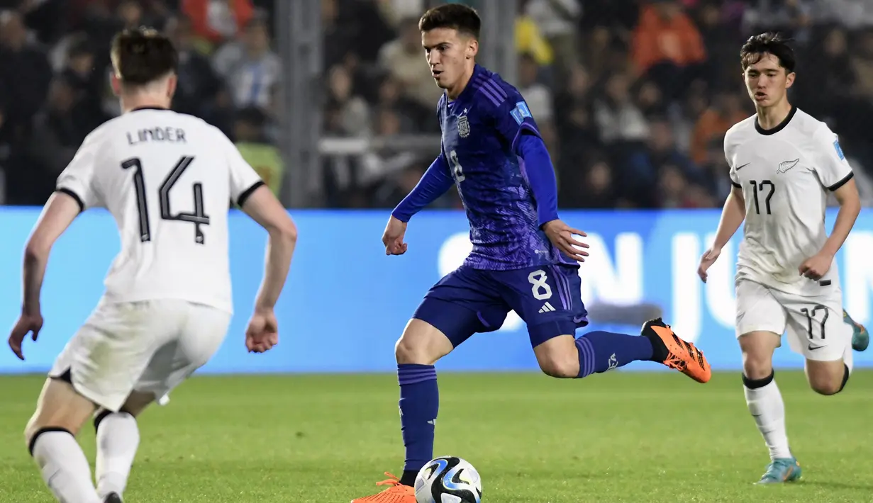 Pemain Argentina U-20, Maximo Perrone menggiring bola melewati sejumlah pemain Selandia Baru U-20 pada laga lanjutan Grup A Piala Dunia U-20 2023 di San Juan Stadium, Argentina, Sabtu (27/05/2023) WIB. Argentina menang dengan skor 5-0. (AFP/Andres Larrovere)