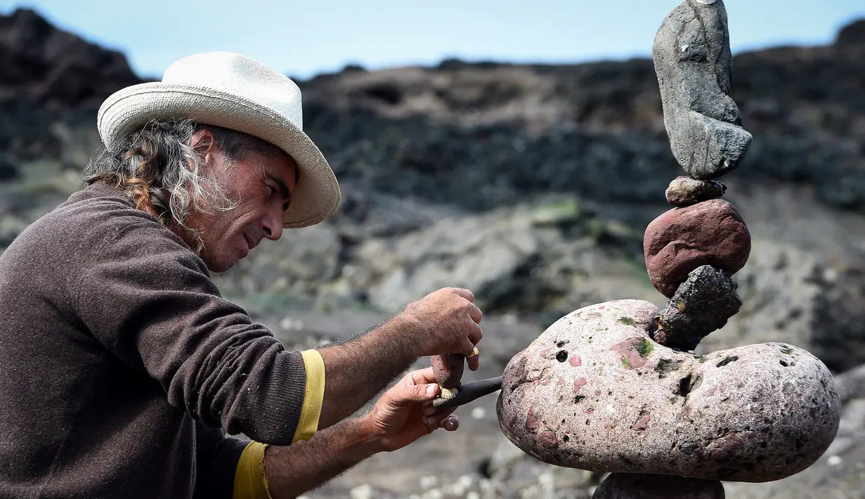 Marco Montesini saat membuat batu bertumpuk atau rock balancing dalam European Stone Stacking Championships 2018 di Dunbar, Skotlandia, Minggu (22/4). Pemenang kejuaraan ini akan diterbangkan ke World Stone Balance Championship di AS. (ANDY BUCHANAN/AFP)