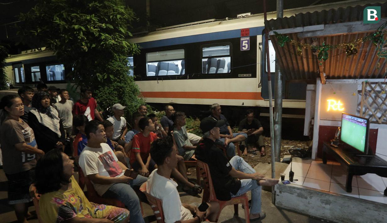 Sejumlah warga menggelar nobar pertandingan Timnas Indonesia melawan Bahrain dalam pertandingan Grup C putaran ketiga Kualifikasi Piala Dunia 2026 zona Asia di kawasan Menteng Jaya, Jakarta, Selasa (25/5/2025). (Bola.com/M Iqbal Ichsan)