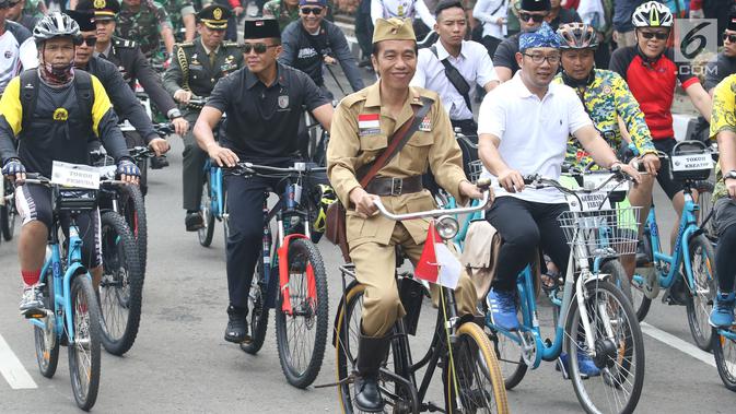 Presiden Joko Widodo atau Jokowi (tengah) didampingi Gubernur Jawa Barat Ridwan Kamil (kanan) saat mengikuti Bandung Lautan Sepeda, Sabtu (10/11). Kegiatan ini dalam rangka memperingati Hari Pahlawan. (Liputan6.com/Angga Yuniar)