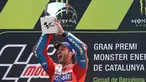 Pembalap Ducati, Andrea Dovizioso mengangkat trofi di podium setelah memenangi MotoGP Catalunya di sirkuit Barcelona Catalunya, Minggu (11/6). Dovizioso berhasil menyelesaikan balapan dengan catatan waktu tercepat 44 menit 41,518 detik. (Josep LAGO/AFP)