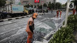 Sejumlah anggota PPSU membersihkan tumpahan oli di kawasan Jalan Thamrin, Jakarta, Selasa (4/10/2022). Sebelumnya jalan ini tercecer tumpahan oli yang membuat jalanan licin. (Liputan6.com/Faizal Fanani)