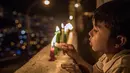 Seorang anak menyalakan lilin selama Hari Lilin Kecil di Medellin, Kolombia (7/12). Hari Lilin Kecil (bahasa Spanyol : Día de las Velitas) adalah salah satu dari hari raya tradisional yang paling dirayakan di Kolombia. (AFP Photo/Joaquin Sarmiento)