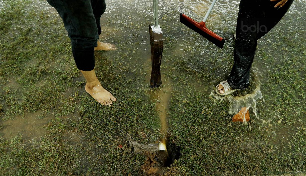 Petugas membuat lubang resapan untuk menguras air yang menggenangi lapangan di Stadion Patriot, Bekasi, Senin (13/11/2017). Drainase yang buruk menyebabkan lapangan terendam air. (Bola.com/M Iqbal Ichsan)