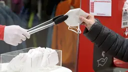 Seseorang mengambil masker FFP2 jenis respirator saat berbelanja di supermarket di Wina, Austria, Senin (25/1/2021). Mulai 25 Januari 2021, warga Austria diwajibkan mengenakan masker FFP2 di supermarket, apotek, pompa bensin, dan di transportasi umum. (AP Photo/Ronald Zak)