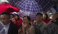 Kerabat dan guru siswa yang mengikuti ujian masuk perguruan tinggi nasional tahunan yang juga dikenal sebagai "Gaokao" menunggu sesi pagi selesai saat hujan turun di Beijing, China, Jumat (7/6/2024). (AP Photo/Ng Han Guan)