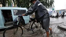 Seorang pengendara sepeda tampak melintas di Jalan Iskandar. Sistem drainase yang buruk menjadi penyebab sejumlah ruas jalan di Ibu Kota selalu digenangi air setiap turun hujan, Jakarta, Kamis (22/1/2015).(Liputan6.com/Miftahul Hayat)