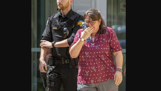 Seorang wanita menangis di dekat polisi usai terjadi penembakan di Robb Elementary School yang berlokasi di Texas. 14 anak tewas.