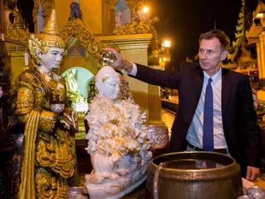 Menteri Luar Negeri Inggris, Jeremy Hunt menuangkan air ke patung Buddha ketika mengunjungi Pagoda Shwedagon di Yangon, Myanmar. Rabu (19/9). Hunt tiba di Myanmar untuk mengunjungi pusat krisis Rohingya dan menemui Aung San Suu Kyi. (AP/ Ye Aung Thu)