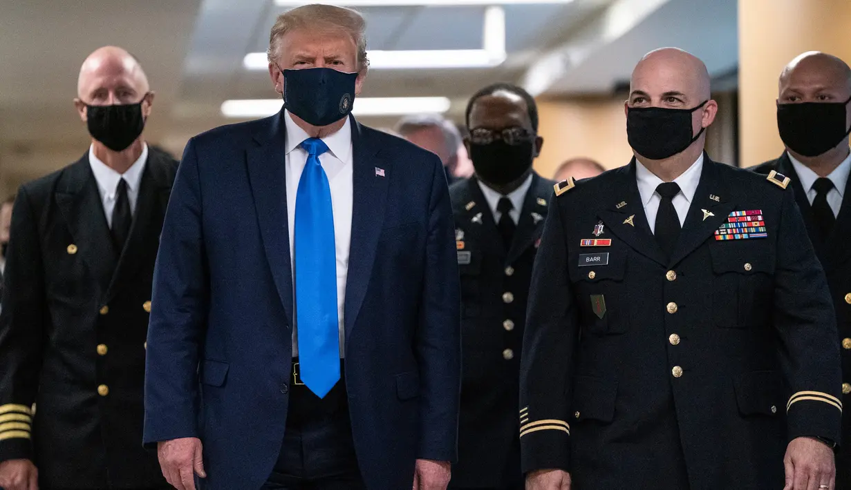 Presiden Amerika Serikat Donald Trump mengenakan masker saat mengunjungi Pusat Kesehatan Militer Nasional Walter Reed di Bethesda, Maryland, Sabtu (11/7/2020). Donald Trump akhirnya menggunakan masker untuk pertama kalinya di depan umum sejak pandemi COVID-19 melanda negara itu.  (ALEX EDELMAN/AFP)