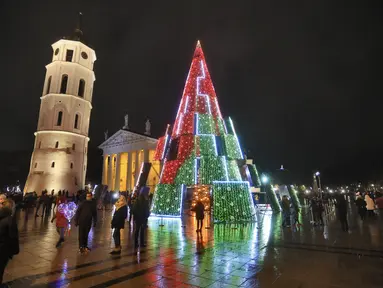 Pohon Natal yang menyala terlihat di dekat katedral di Vilnius, Lithuania pada 28 November 2020. Pohon natal raksasa yang dihiasi berbagai ornamen lampu hias tersebut membuat kawasan di ibu kota Lithuania menjadi terang. (PETRAS MALUKAS / AFP)