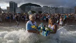 Penganut kepercayaan Afro-Brasil melarung persembahan untuk Dewi Laut, Yemanja dalam tradisi upacara menjelang tahun baru di pantai Copacabana, Rio de Janeiro, Sabtu (29/12). Ritual dilakukan untuk mendapat berkat di tahun yang akan datang (AP/Leo Correa)