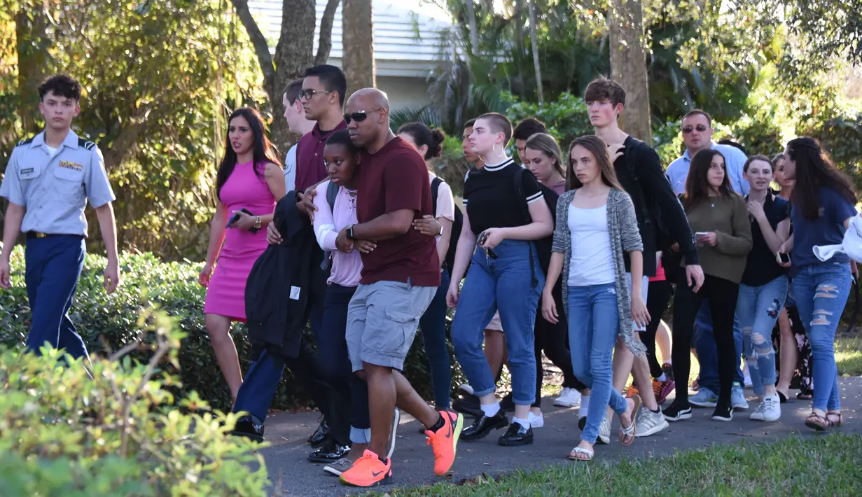 Sejumlah siswa dievakuasi ketika terjadi  penembakan massal sekolah menengah atas Marjory Stoneman Douglas di Parkland, Florida, Rabu (14/2). Insiden itu melukai sejumlah orang dan membuat ratusan murid berlarian ke jalanan. (Michele Eve Sandberg/AFP)