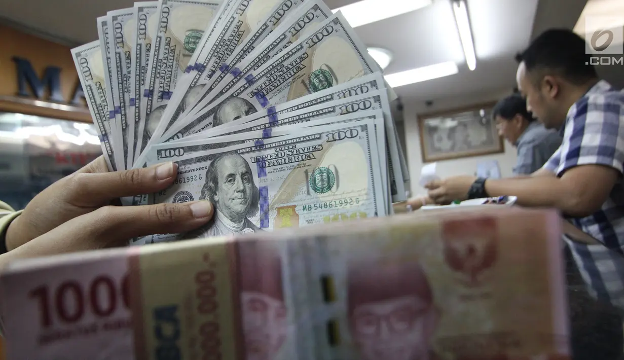 Teller menunjukkan uang dolar dan rupiah di penukaran uang di Jakarta, Junat (23/11). Nilai tukar dolar AS terpantau terus melemah terhadap rupiah hingga ke level Rp 14.504. (Liputan6.com/Angga Yuniar)