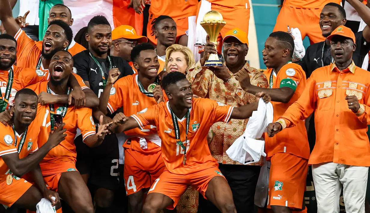 Presiden Pantai Gading Alassane Ouattara (tengah) mengangkat trofi Piala Afrika di podium setelah Les Elephants memenangkan pertandingan sepak bola final Piala Afrika (CAN) melawan Nigeria di Stadion Olimpiade Alassane Ouattara, Ebimpe, Abidjan pada 11 Februari 2024. (FRANCK FIFE/AFP)