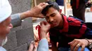 Seorang pria Yaman mengoleskan kosmetik tradisional kohl ke kelopak mata pria lain di Masjid Agung, kota tua Sanaa pada 9 mei 2019. Bagi muslim Yaman, pemakaian kohl diyakini mampu membersihkan dan melindungi mata dari penyakit ini sudah menjadi tradisi setiap bulan Ramadan. (MOHAMMED HUWAIS/AFP)