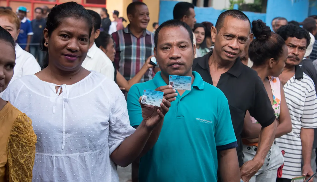 Warga Timor Leste menunjukkan kartu identitasnya saat mengantre untuk menggunakan hak pilih mereka di tempat pemungutan suara (TPS) di Dili, Senin (20/3). Sedikitnya 1,2 juta warga akan memilih presiden baru Timor Leste. (Valentino DARIEL SOUSA/AFP)