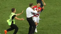 Seorang penyusup mendekati bek timnas Kroasia, Dejan Lovren dalam laga final Piala Dunia 2018 melawan Prancis di Luzhniki Stadium, Minggu (15/7). Pertandingan sempat dihentikan sebelum para penyusup ditangkap oleh petugas. (AP/Thanassis Stavrakis)