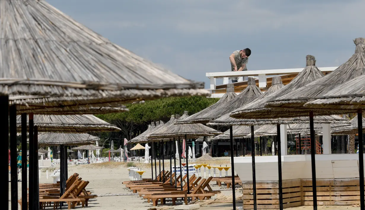Seorang pekerja memperbaiki atap bar di sebuah pantai di Qerret, dekat kota Kavaja, Albania pada 1 Juni 2020. Rencananya pada 6 Juni mendatang, semua pantai umum akan dibuka untuk wisatawan setelah Albania menerapkan langkah-langkah pelonggaran pencegahan virus corona. (SHKULLAKU / AFP)