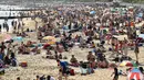 Orang-orang menikmati sinar matahari di pantai dekat Dermaga Bournemouth di Bournemouth, Inggris, Senin (25/5/2020). Inggris mulai melonggarkan beberapa pembatasan yang diberlakukan untuk mengendalikan penyebaran virus corona Covid-19. (Photo by Glyn KIRK / AFP)