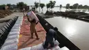 Para petani memuat sekantong benih jagung ke dalam perahu saat mereka mengungsi dari daerah banjir di kota Burewala, di distrik Vehari di provinsi Punjab, pada 25 Agustus 2023. (AFP/Shahid Saeed Mirza)