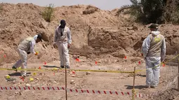 Pakar forensik yang bekerja untuk otoritas Irak, menggali dan sejumlah sisa-sisa manusia ditemukan di kuburan massal dekat kota selatan Najaf, pada 14 Mei 2022. Kuburan massal itu, pertama kali ditemukan pada April tahun ini, diyakini menampung puluhan orang yang kemungkinan besar tewas di bawah mendiang diktator Saddam Hussein, kata seorang pejabat. (AFP)