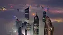 Suhu dingin dan kelembapan tinggi selama malam dan dini hari menciptakan kondisi ideal untuk terbentuknya kabut. Tampak foto udara memperlihatkan gedung pencakar langit yang tertutup kabut pagi di Kota Kuwait pada Minggu 9 November 2025. (YASSER AL-ZAYYAT/AFP)