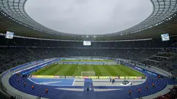 Para pemain melakukan pemanasan di dekat Replika Tembok Berlin bertuliskan "Bersatu menentang tembok.Bersatu untuk Berlin" berdiri jelang pertandingan Hertha Berlin melawan RB Leipzig di Stadion Olimpiade, Berlin (9/11/2019). (AFP/Odd Andersen)
