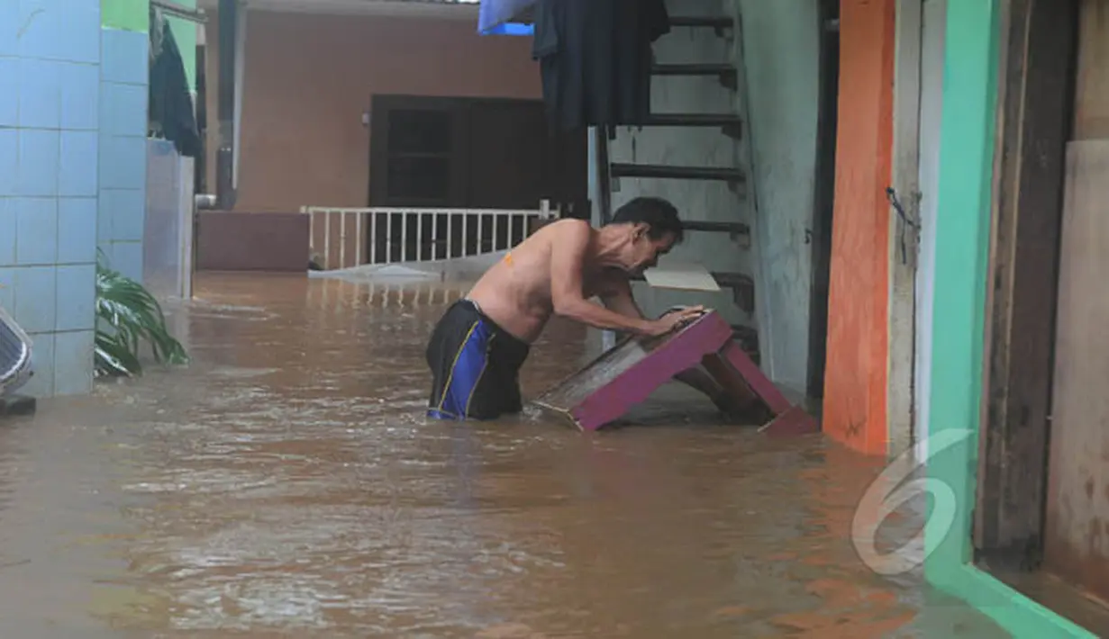 Warga tampak membersihkan meja yang terendam banjir di kawasan Kampung Pulo, Jatinegara, Jakarta Timur, Selasa (10/2/2015). (Liputan6.com/Herman Zakharia)