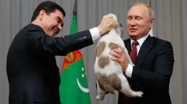 Presiden Rusia, Vladimir Putin (kanan) menerima anjing gembala Turkmen atau dikenal sebagai Alabai dari Presiden Turkmenistan Gurbanguly Berdimuhamedov saat pertemuan di Sochi, Rusia (11/10). (AFP Photo/Pool/Maxim Shemetov)