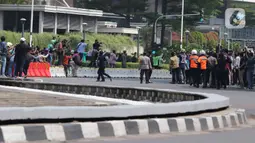Warga berkumpul dan mengambil gambar parade pembalap MotoGP di kawasan Jakarta, Rabu (16/3/2022).  Sebanyak 20 pembalap MotoGP menjajal ruas Jalan Sudirman-Thamrin, Jakarta Pusat hari ini. (Liputan6.com/Herman Zakharia)