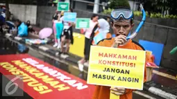 Seorang pria yang tergabung dalam ICW menunjukan poster saat menggelar aksinya di Car Free Day dikawasan Bunderan HI, Jakarta, Minggu (12/2). Menurut pihak ICW lembaga peradilan saat ini butuh diselamatkan. (Liputan6.com/Faizal Fanani)