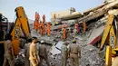 Tim penyelamat mencari korban yang terjebak reruntuhan gedung enam lantai yang ambruk di desa Shahberi, pinggiran kota New Delhi, India, Rabu (18/7). Peralatan berat  digunakan untuk mencari para korban. (AP Photo/Altaf Qadri)