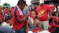 Salah satu pelukis cat wajah sedang melukis wajah salah satu pendukung Timnas Indonesia jelang laga melawan Malaysia di Stadion Shah Alam, Selangor, Sabtu (26/8/2017). (Liputan6.com/Cakrayauri Nuralam)