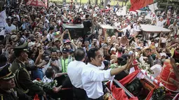Jokowi-JK terus melempar senyum dan melambaikan tangan kepada ratusan warga yang menunggunya, Jakarta, (20/10/14). (Liputan6.com/Faizal Fanani) 