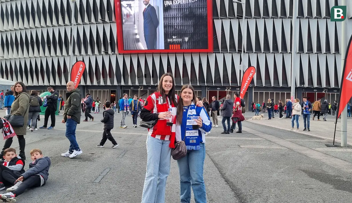 Dua fans perempuan Athletic Bilbao (kiri) dan Real Sociedad berfoto bersama dengan latar Stadion San Mames, Bilbao, Spanyol menjelang laga lanjutan Liga Spanyol 2023/2024 antara Athletic Bilbao dan Real Sociedad, 13 Januari 2024. (Bola.com/Yus Mei Sawitri)