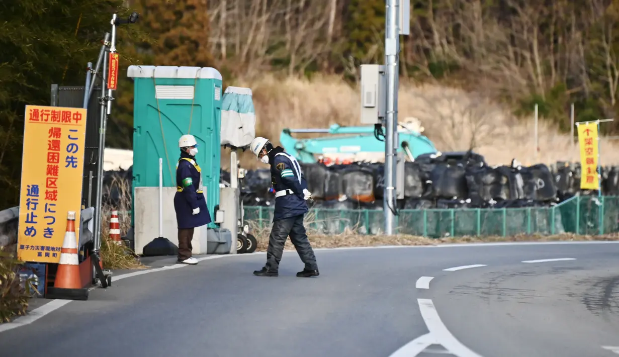Petugas mengontrol akses area terlarang di Tomioka, prefektur Fukushima, tepat di sebelah utara PLTN Daiichi Daiichi Fukushima yang rusak parah akibat gempa bumi dan tsunami 2011. Jepang pada 4 Maret 2020 resmi mencabut perintah evakuasi di bagian Futaba, Fukushima. (AFP/Charly Triballeau)
