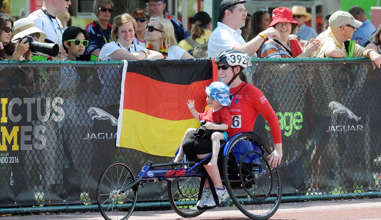 Seorang peserta mendapat sambutan hangat dari penonton saat menggendong anaknya  pada ajang Invictus Games Orlando 2016 di ESPN Wide World of Sports complex, (10/5/2016), Lake Buena Vista, Florida.   (Gerardo Mora/Getty Images for Invictus Games/AFP)