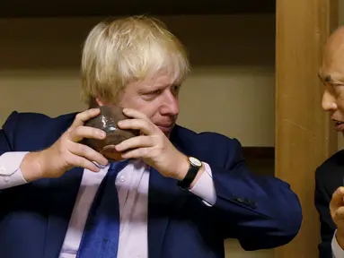 Walikota London Boris Johnson (kiri) saat menikmati teh yang disuguhkan dalam perjamuan teh  di Kuil Meiji, Tokyo, Rabu (14/10/2015). Johnson berada di jepang untuk menjalin kerja sama di bidang perdagangan dan budaya. (REUTERS/Issei Kato)
