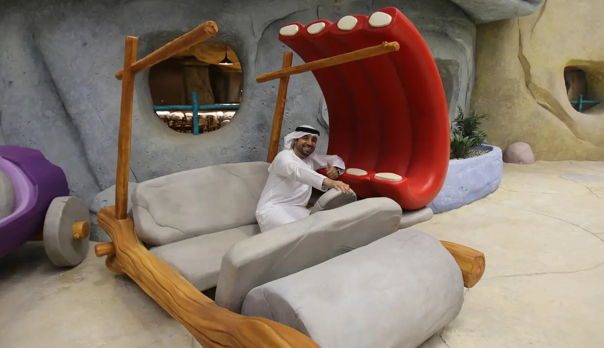 Seorang pejabat Uni Emirat Arab berpose dengan mobil tiruan Fred Flintstone di taman hiburan Warner Bros, Abu Dhabi, 18 April 2018. Hadirnya taman hiburan ini juga menjadi pelengkap untuk menarik turis datang ke Uni Emirat Arab. (AP/Kamran Jebreili)