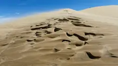 Seorang turis berdiri di atas bukit pasir Taman Nasional Altynemel, Almaty, Kazakhstan, 12 Mei 2016. Bukit pasir yang membentang hingga 3 km dan tinggi 30 m ini dapat menghasilkan gemuruh bernada rendah yang seolah-olah bernyanyi (REUTERS/Shamil Zhumatov)