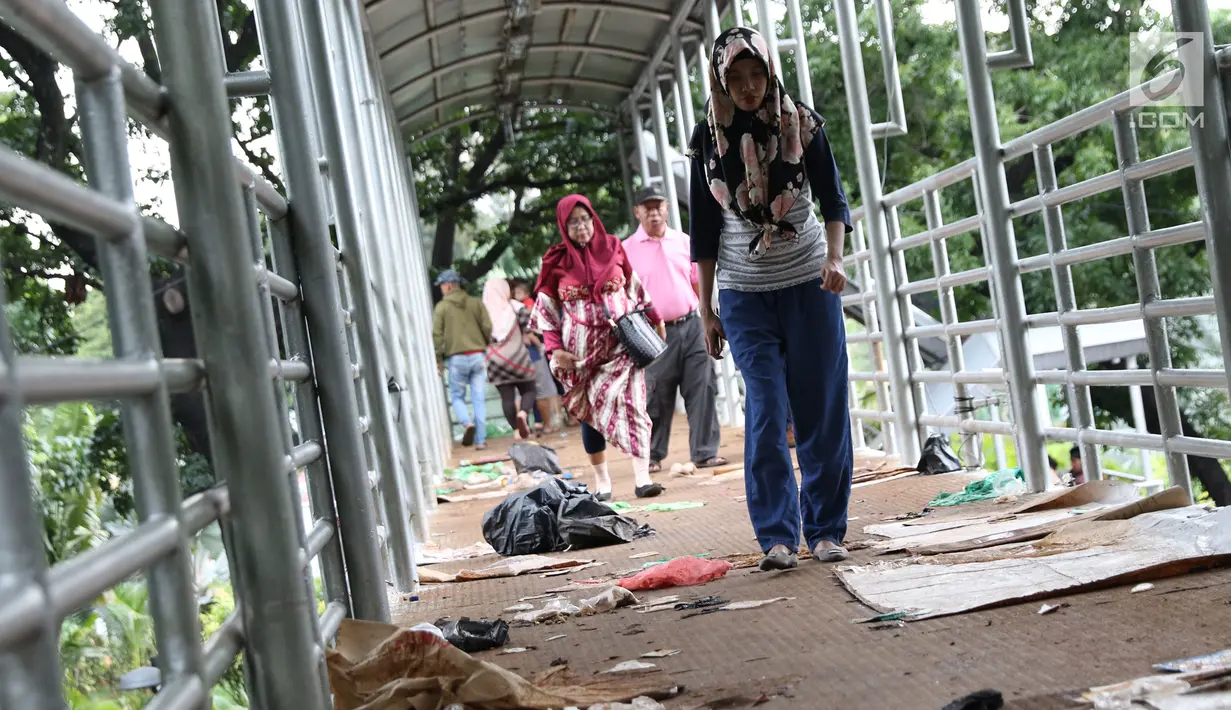 Warga melintas di antara ceceran sampah di koridor Jembatan Penyebrangan Orang (JPO) Jalan Medan Merdeka Barat, Jakarta, Selasa (1/1). Pasca malam perayaan pergantian tahun JPO Medan Merdeka Barat masih tampak kotor. (Liputan6.com/Helmi Fithriansyah)