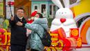 Sebuah keluarga berswafoto dengan patung kelinci saat pekan liburan Tahun Baru Imlek di taman umum di Beijing, China, Kamis (26/1/2023). (AP Photo/Mark Schiefelbein)
