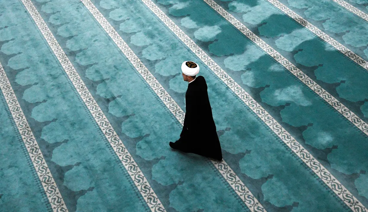 Seorang imam berjalan melintasi aula di Masjid Katedral Moskow, Rusia, Kamis (23/5/2019). Masjid yang dibangun pada tahun 1904 ini selalu ramai oleh aktivitas umat muslim selama Ramadan. (Kirill KUDRYAVTSEV/AFP)